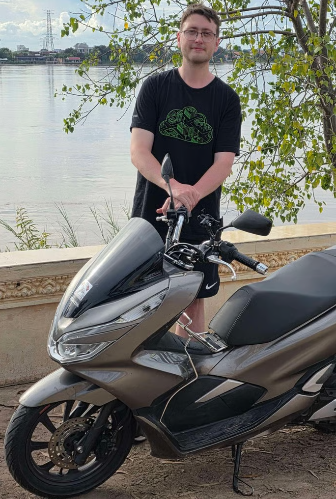 Jamie Blair beside a motorbike at the Mekong River in Phnom Penh, Cambodia