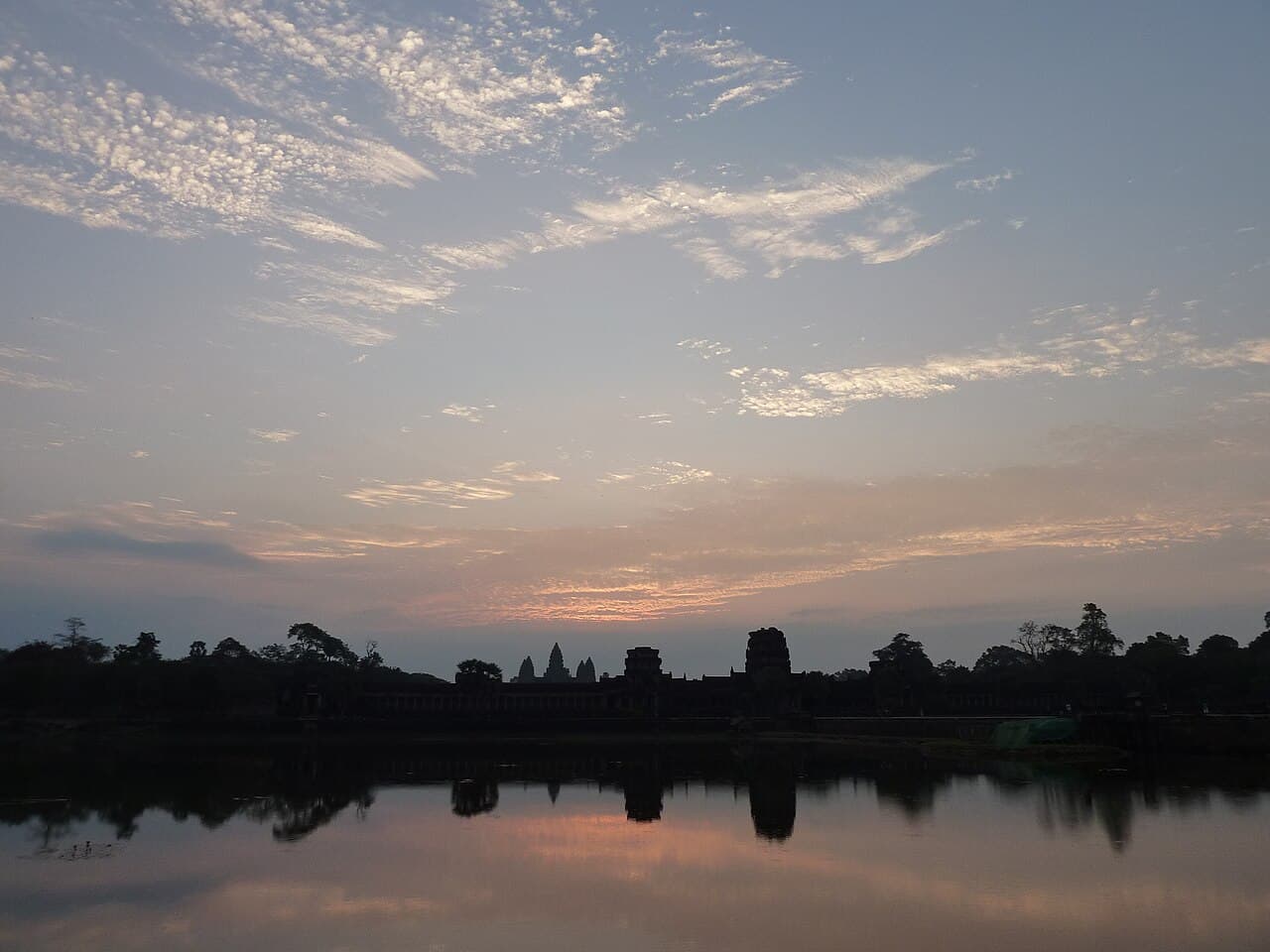 Sunrise behind the towers of Angkor Wat, reflected in the moat.